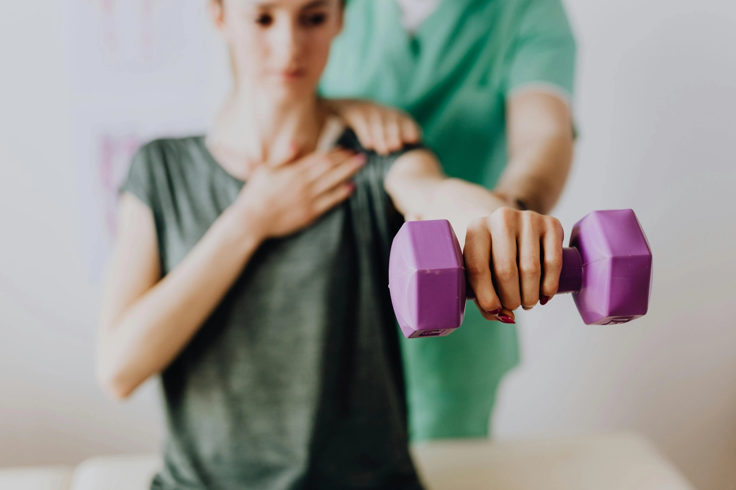 Osteopathie am Park – Ganzheitliche Behandlung – Dieses Bild zeigt offenbar eine Physiotherapie-Sitzung, in der ein Therapeut einen Patienten bei Rehabilitationsübungen zur Kräftigung der Schulter oder der Rotatorenmanschette unterstützt.